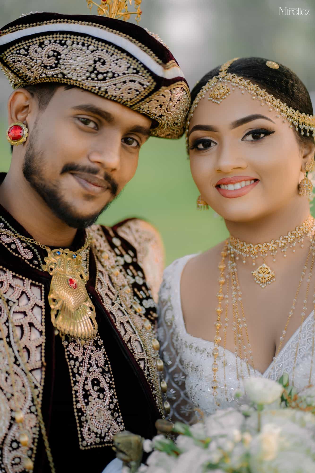 Close-up portrait of Isuru and Supuni in Kandyan wedding regalia, the groom in a jewelled nilame hat, the bride in a pearl headpiece