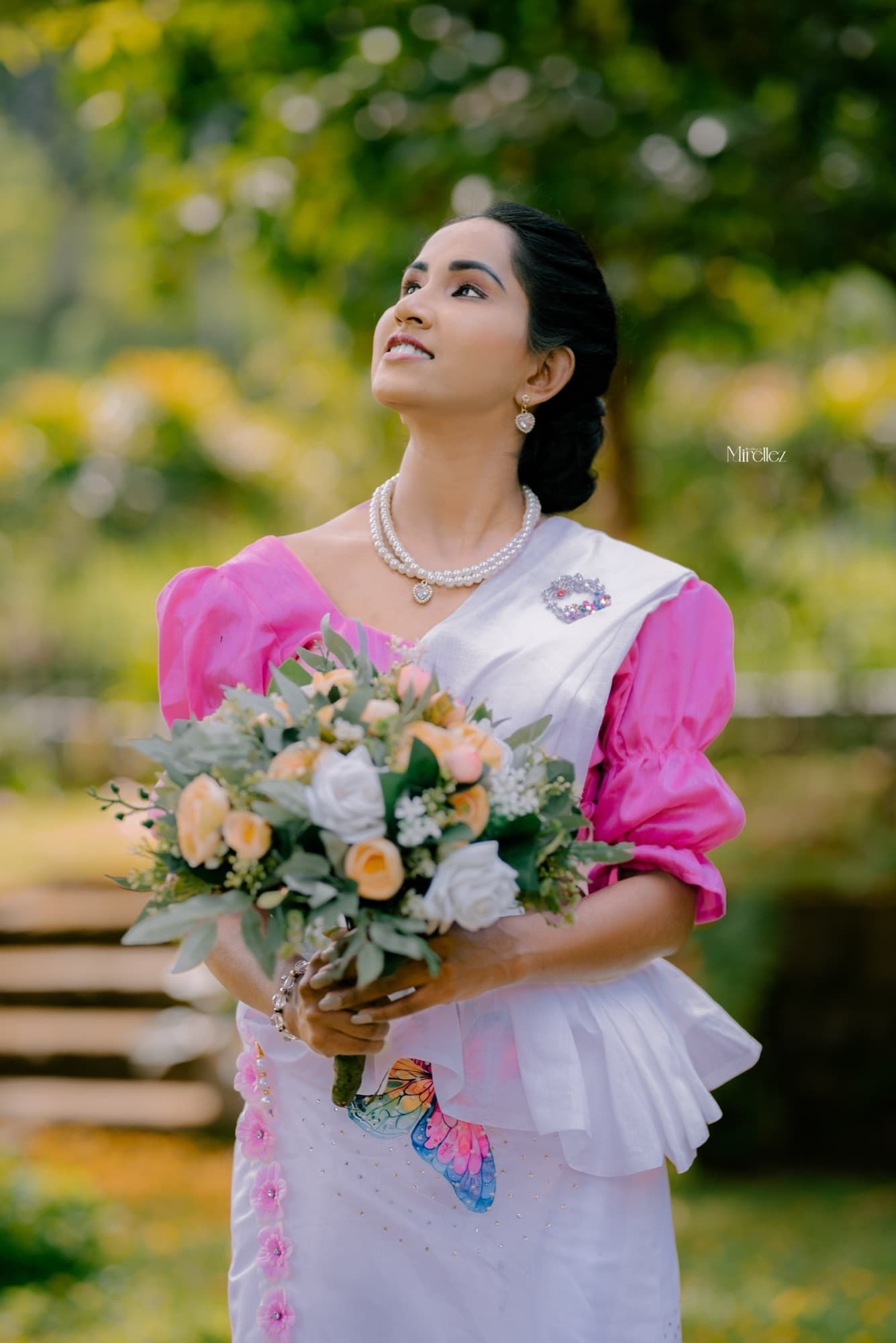 Solo portrait of the bride looking upward in soft morning light, holding a pastel rose bouquet