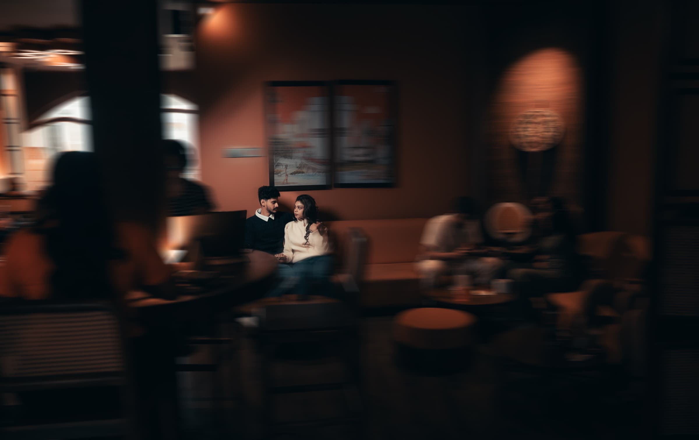A couple in a warm, dimly lit lounge captured through a soft motion-blurred frame